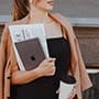 Frau mit Laptop und Papieren in der Hand