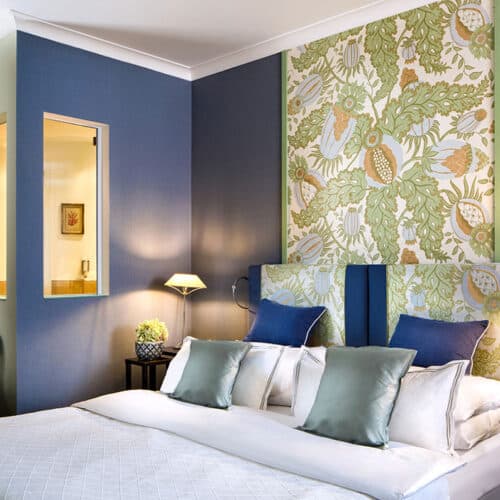 Ansicht Deluxezimmer mit Bett, blauer Wand und grüner Blumentapete
