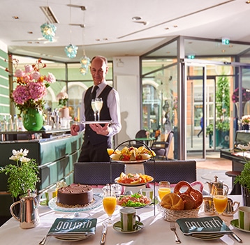 Reichhaltig gedeckter Frühstückstisch mit Kellner im Hotel Goliath